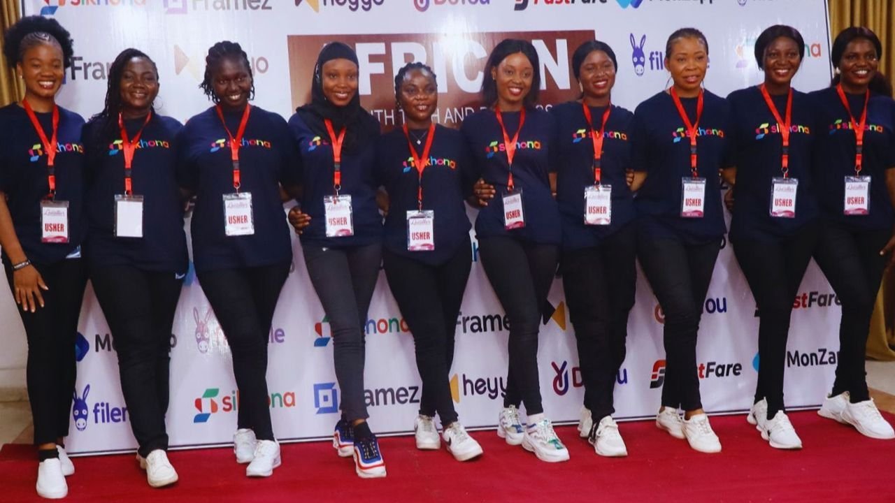Women standing together on a red carpet for a group photo at Sikhona.